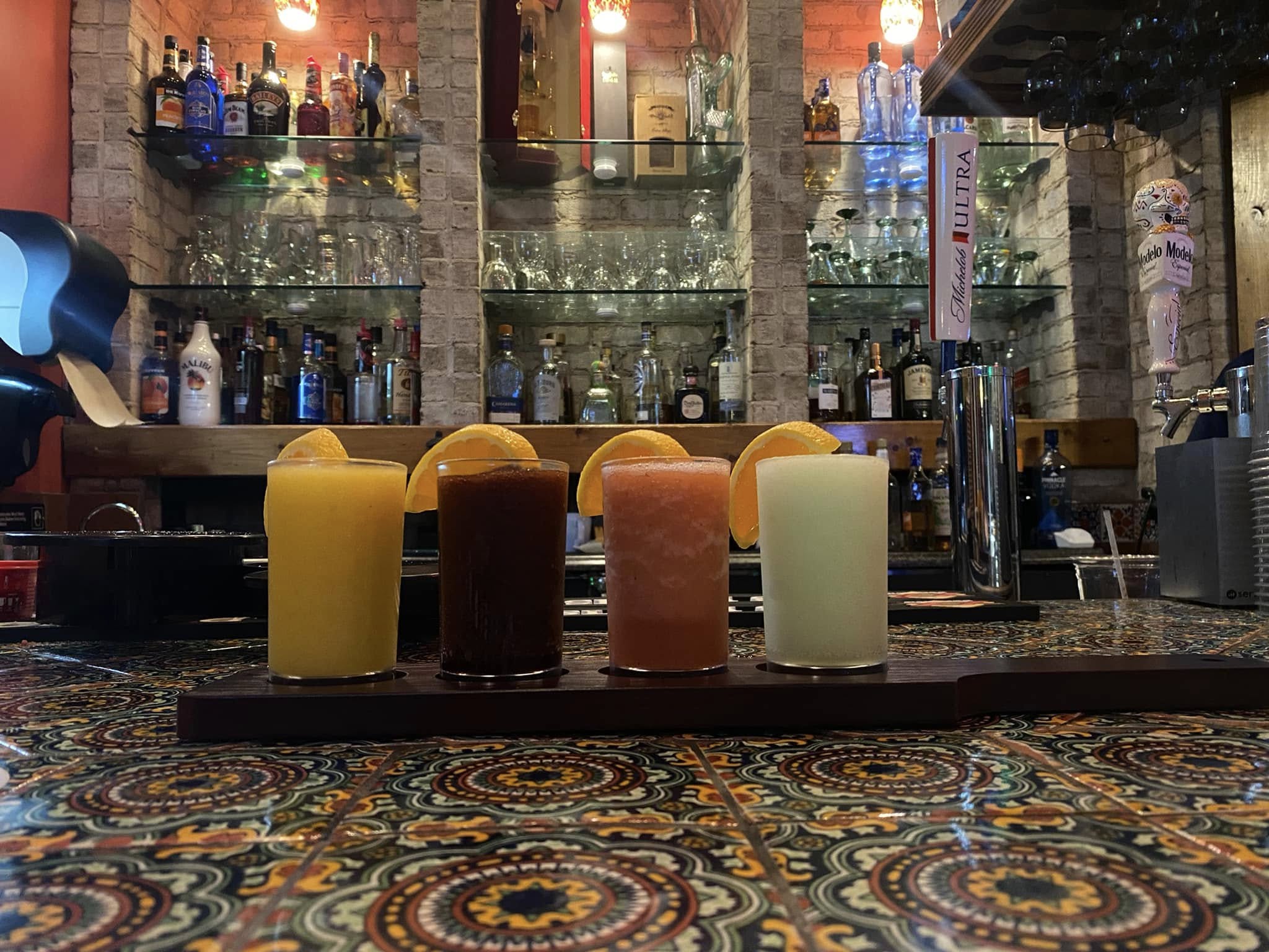 el olmeca frozen margarita flight on a board sitting on a bar