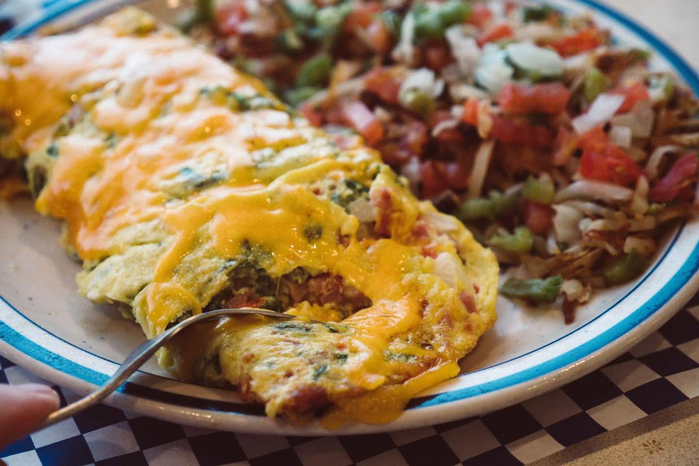 three ingredient omelette with a few extra ingredients (cheddar cheese, onion, tomato, spinach, green peppers) and scattered hash browns topped with the the same vegetables, or your choice of ingredient